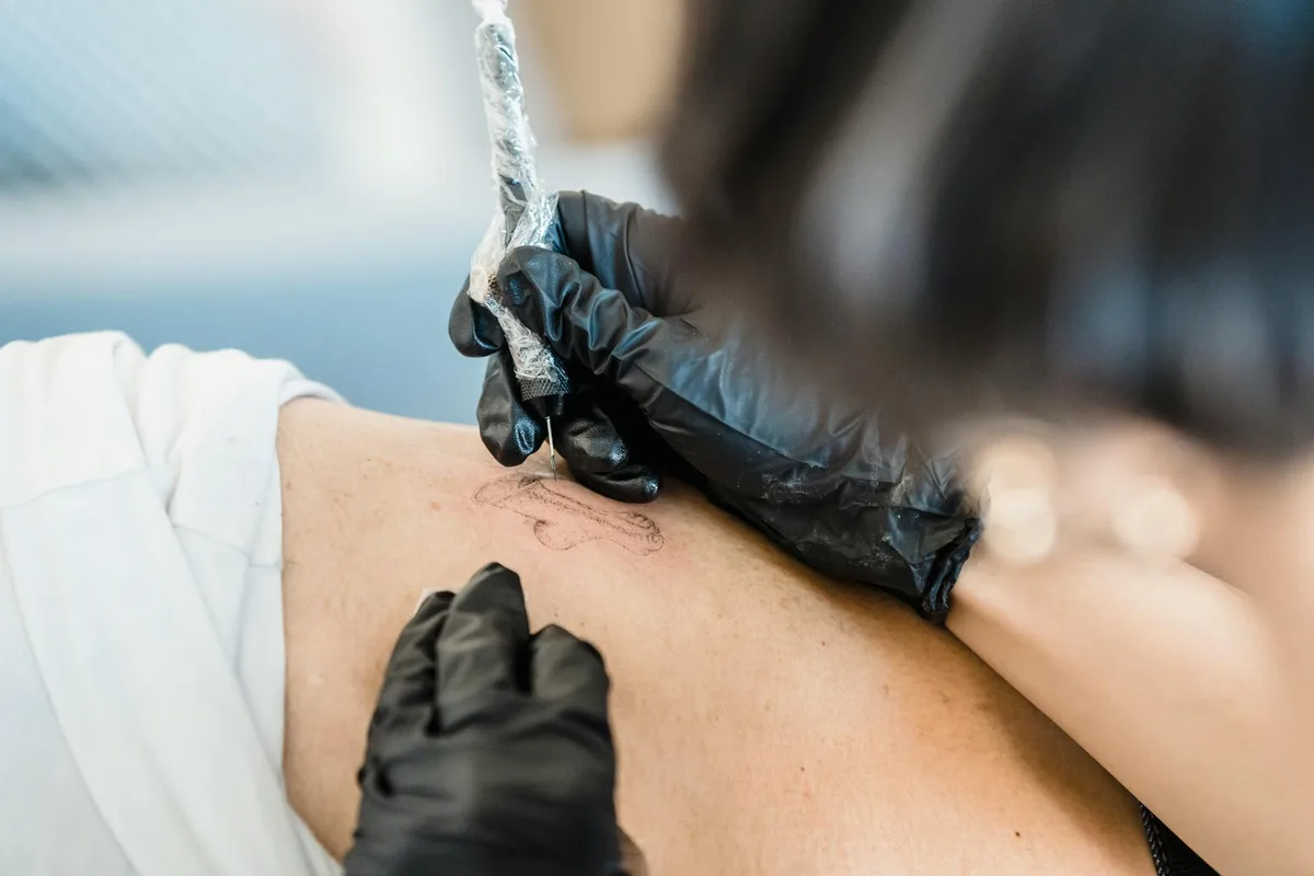Close-up of a tattoo artist skillfully applying a tattoo, showcasing precision and artistry.