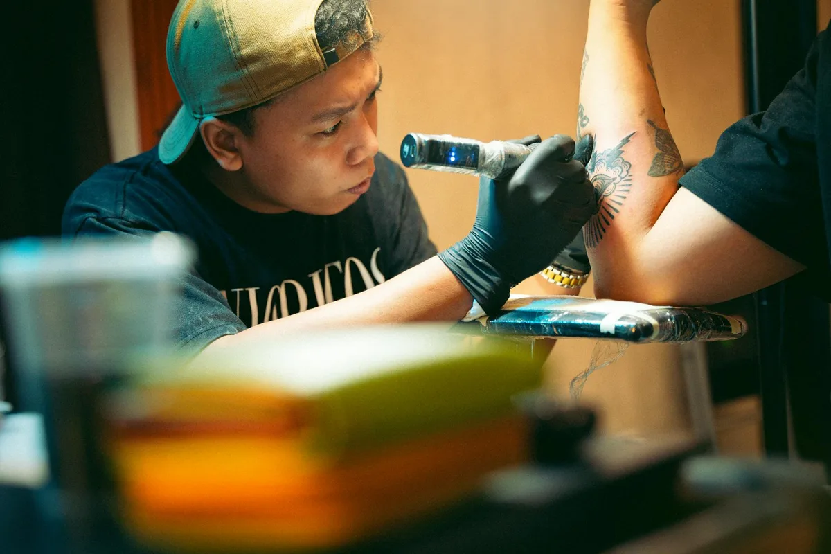 Tattoo artist focusing on intricate arm design in studio setting.