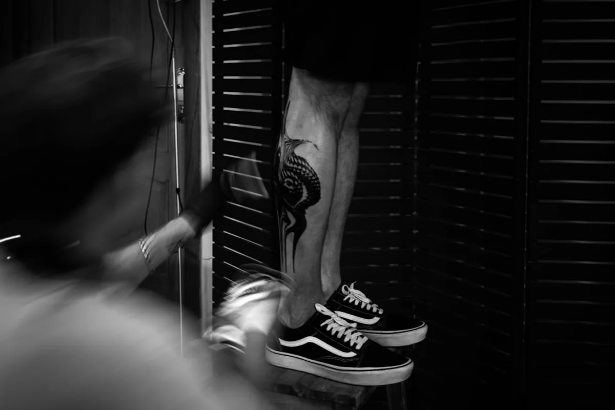 a man with a tattoo on his leg standing on a stool