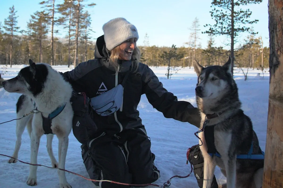 A man sitting next to two dogs in the snow