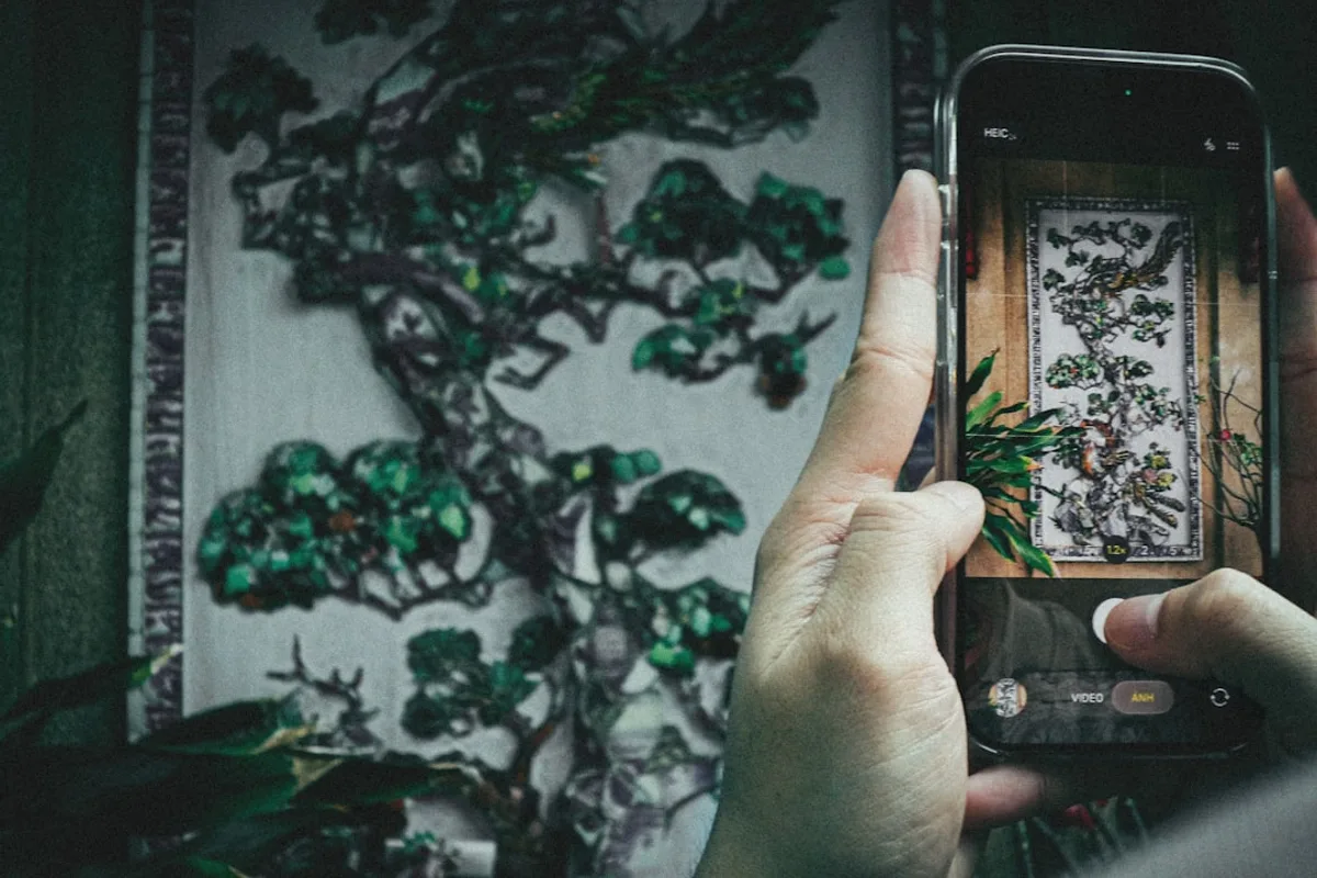Person taking a picture of a detailed tree artwork.
