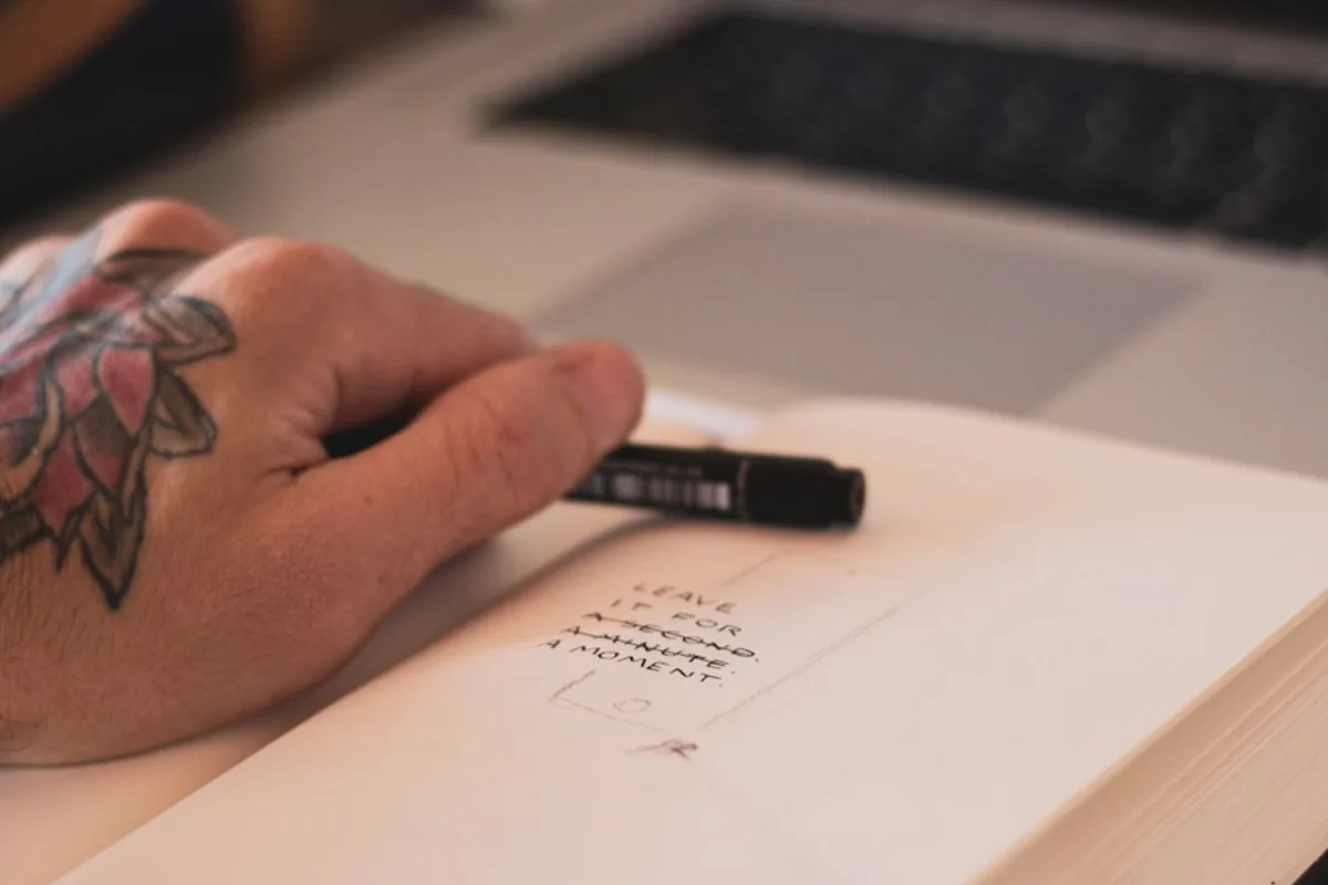 person holding ballpoint pen on opened book