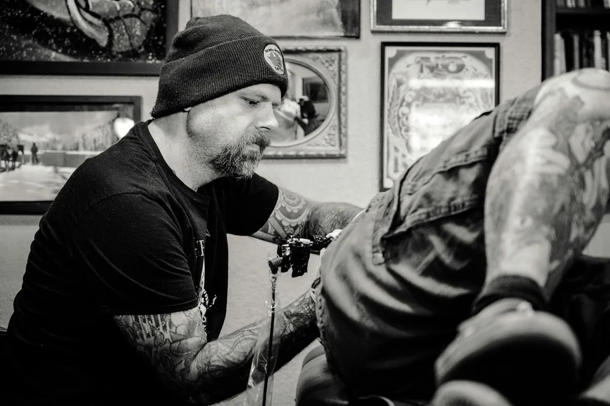 Tattoo artist focused on creating a design in a studio setting.