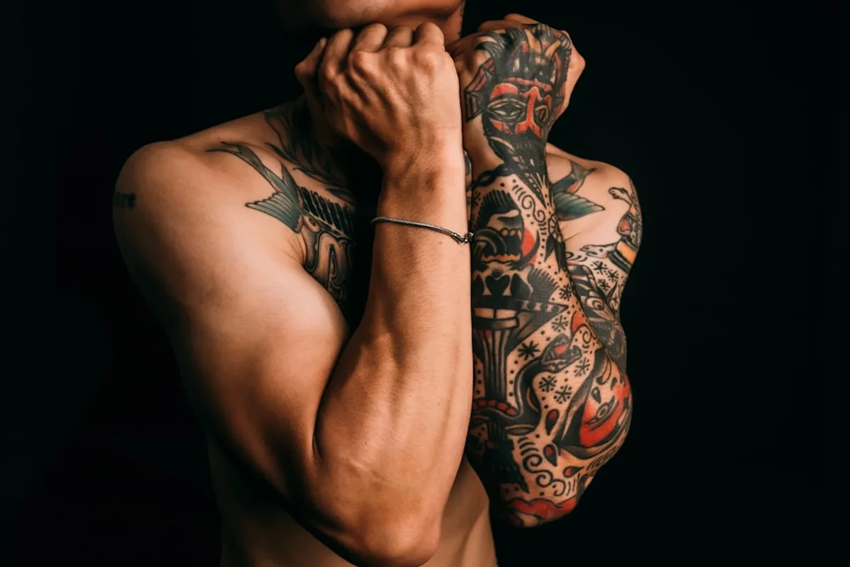Man with fully tattooed arms against black background