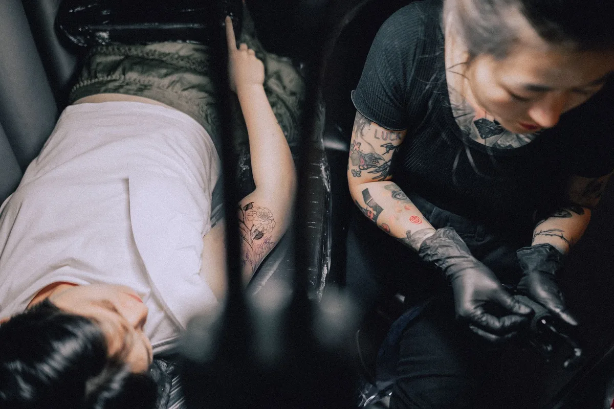 Tattoo artist creating a new tattoo for a client in a professional studio environment.