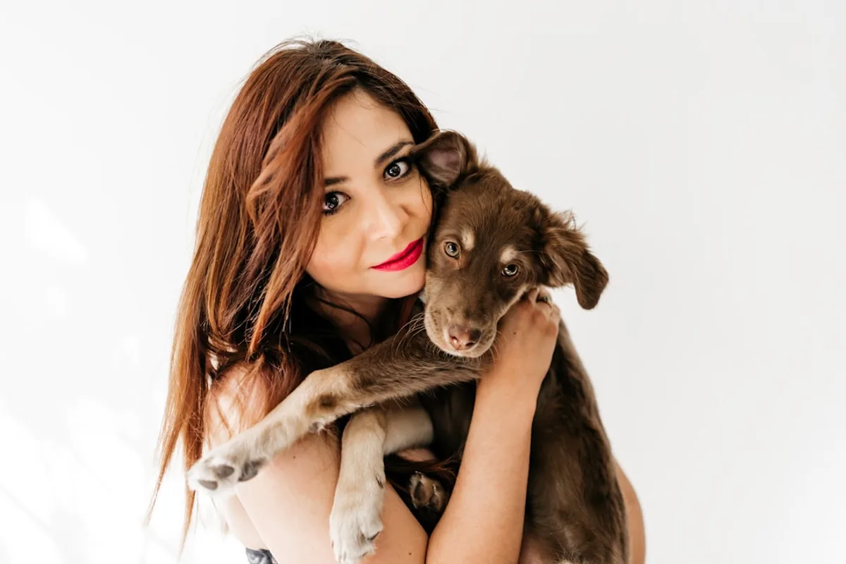 woman in black tank top hugging brown short coated dog