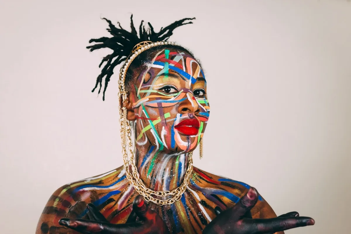 Woman poses with colorful face and body art.