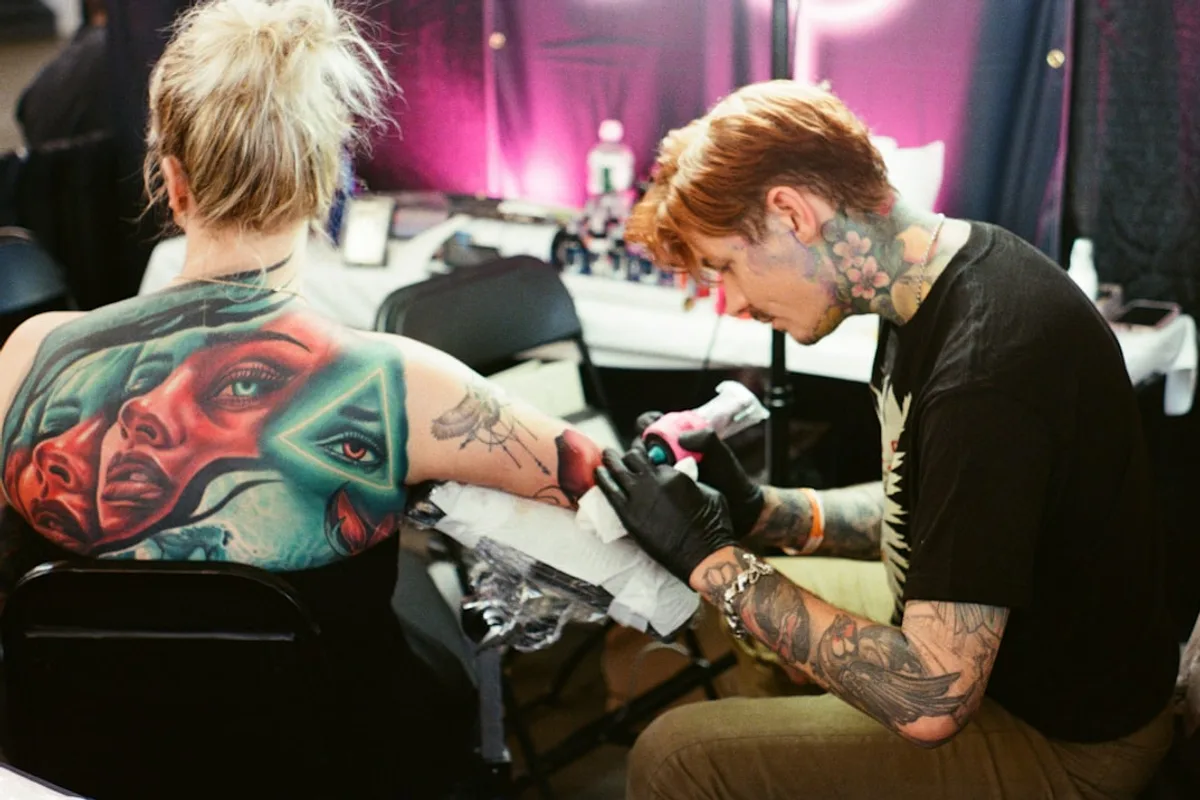 Tattoo artist working on a client's arm