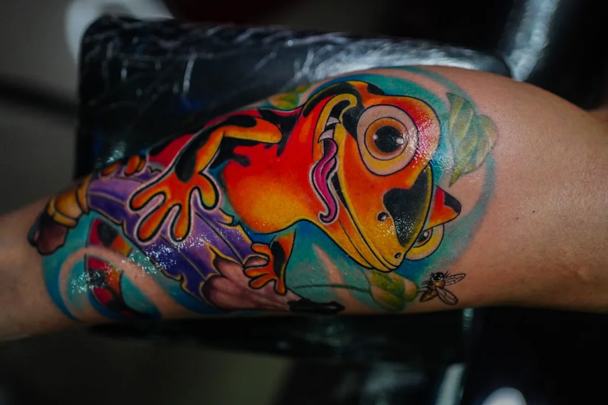 a colorful tattoo of a frog on the arm