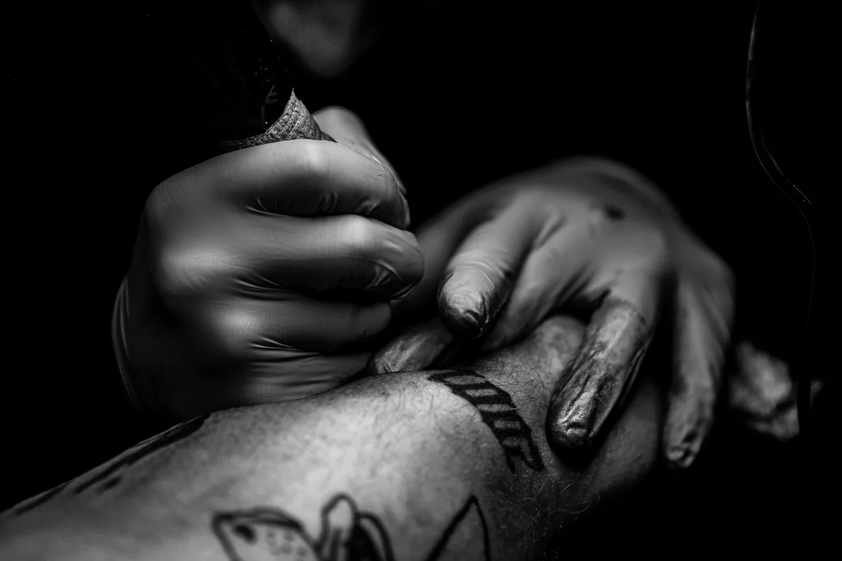 A detailed close-up of a tattoo being applied in black and white.