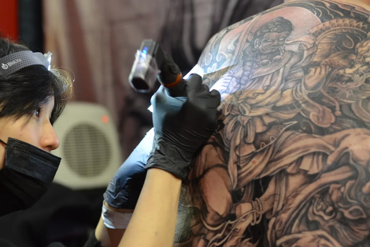 a woman getting a tattoo done on her back