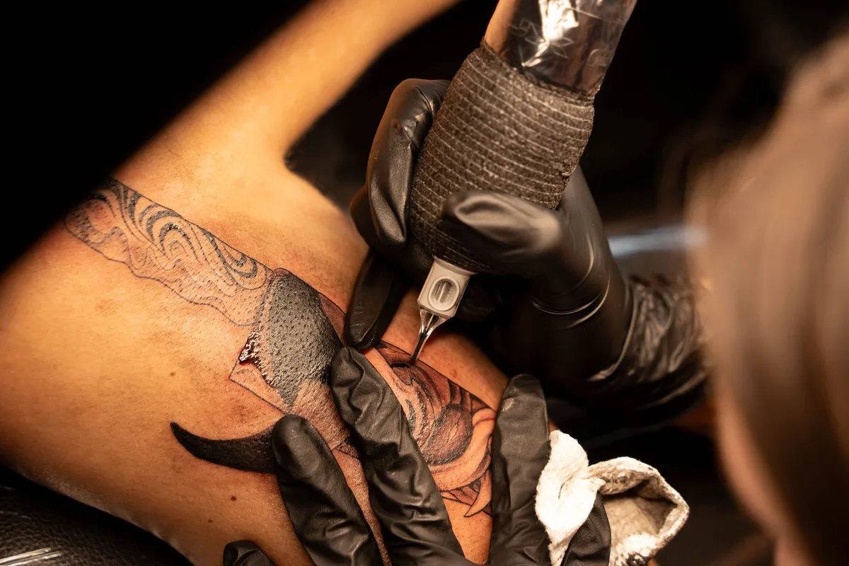 A tattoo artist skillfully working on an intricate design with precision needles.