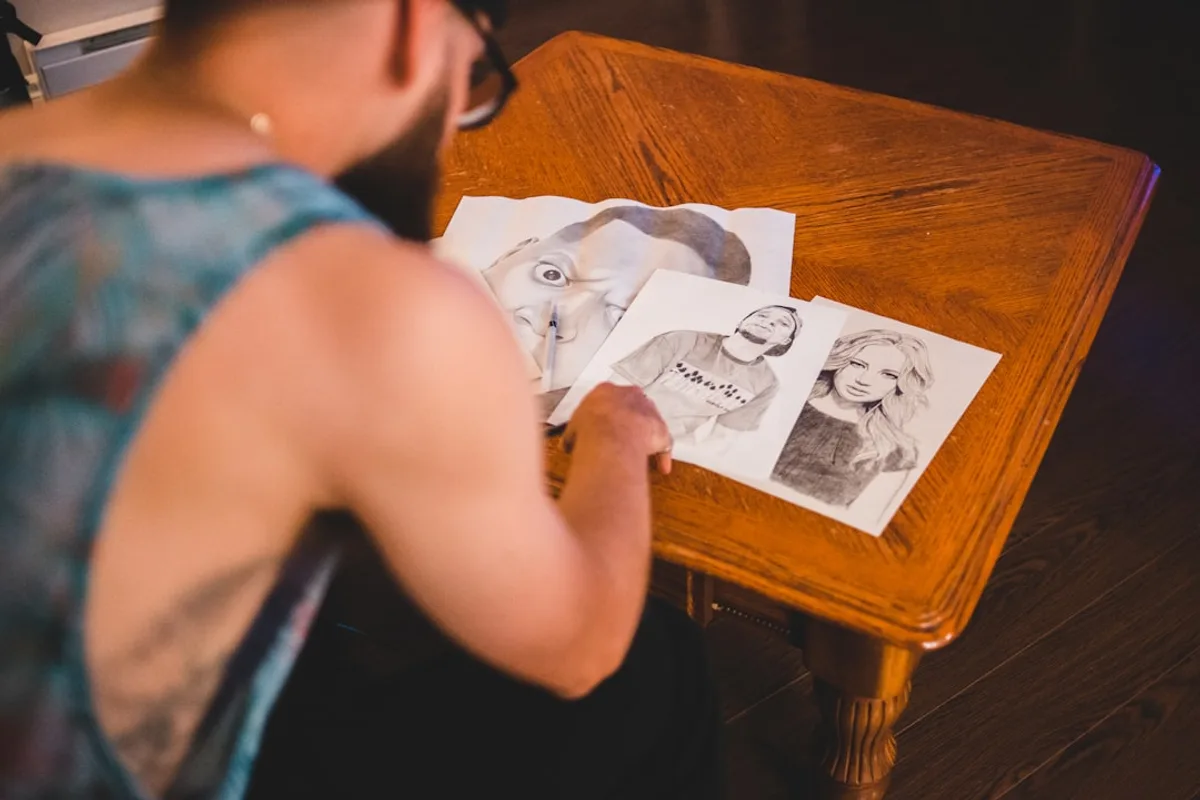 man standing in front of brown wooden side table with three drawings