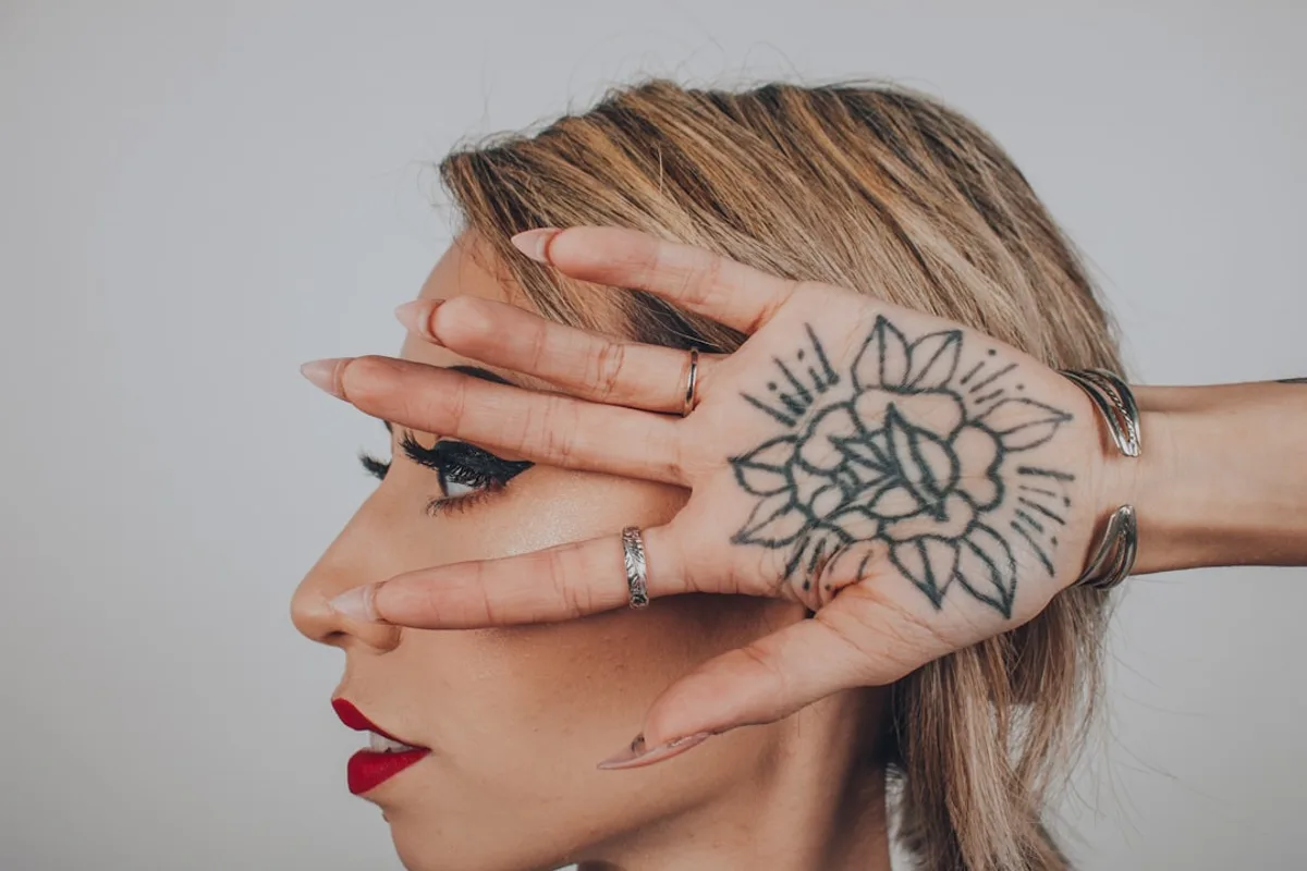 woman with black flower tattoo in palm