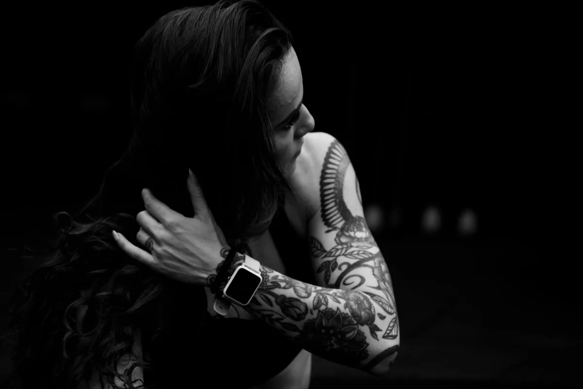 Artistic black and white portrait of a tattooed woman in dramatic lighting.
