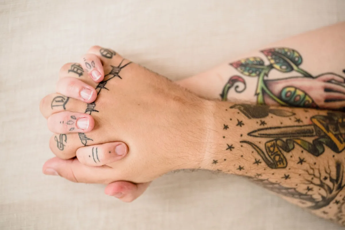 Two tattooed hands clasped together, symbolizing love and connection.