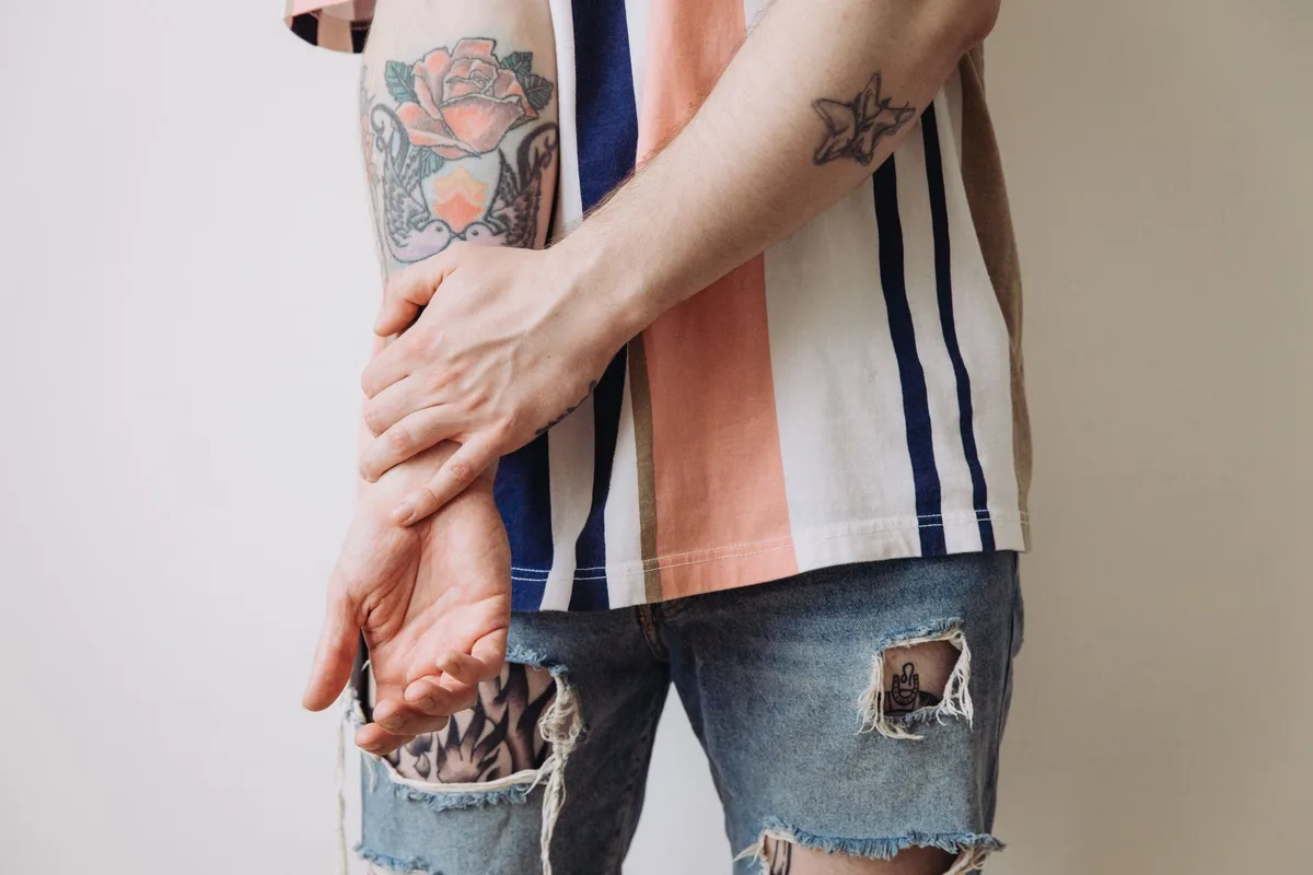 Detailed shot of tattooed arms in a striped shirt. Casual and stylish fashion.