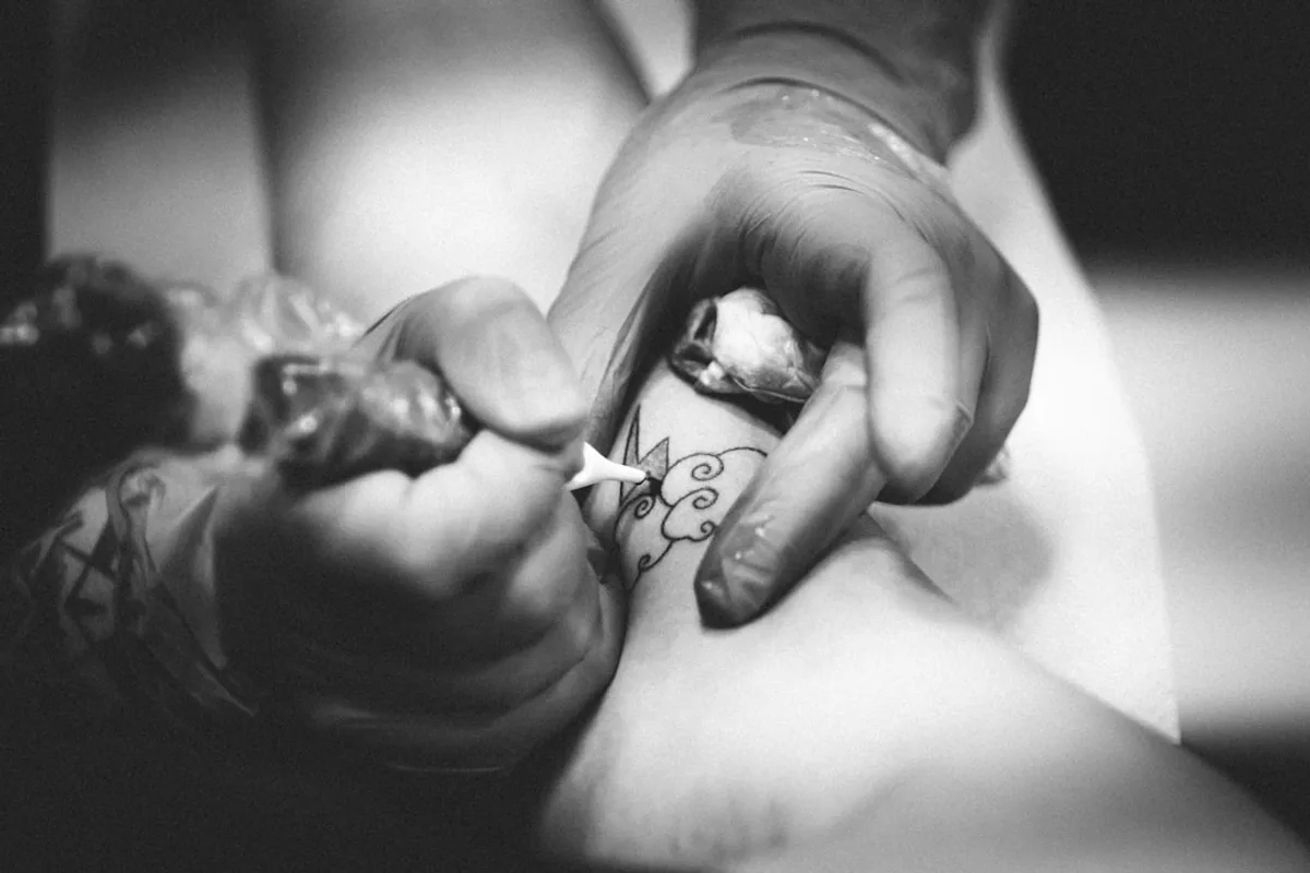 person doing flower tattoo on leg